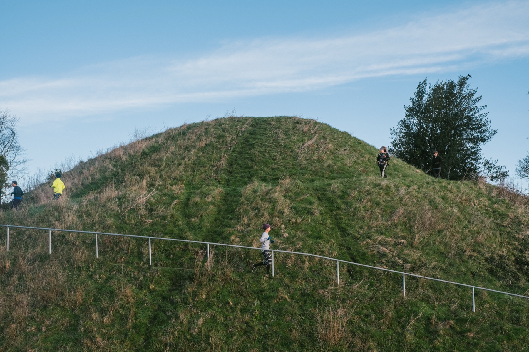 The Mount in Lewes — a steep grassy mound with a path up it, one person walking, under a wide pale sky